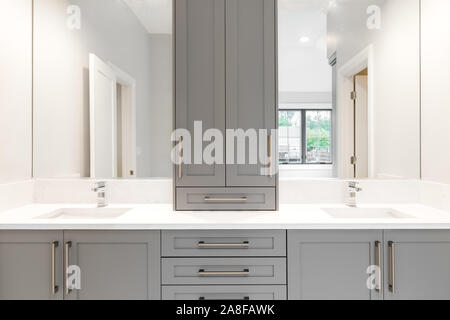 Un vanity gris dans une grande salle de bains luxueuse avec comptoirs en granite et d'installation de chrome. Banque D'Images