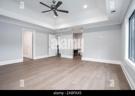 Un grand vide, une chambre principale avec un plafond élevé, un ventilateur de plafond suspendu dans le milieu, et planchers de bois partout. Banque D'Images