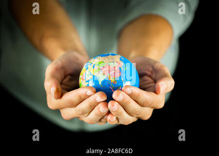 Male hands holding the Earth globe sur fond noir Banque D'Images