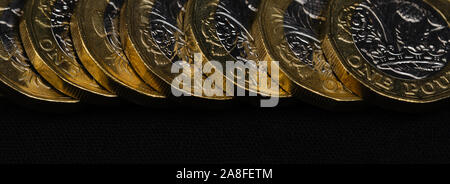 Close up of British pound coins d'affilée sur fond noir, taille de bannière web Banque D'Images