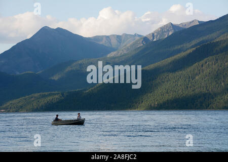 Deux personnes dans un bateau à moteur dans la région de Kootenay Lake, avec les montagnes de la Purcell Wilderness Conservancy en arrière-plan, en Colombie-Britannique, Canada. Banque D'Images