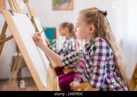 Enfants de dessiner sur un chevalet dans l'école d'art Banque D'Images