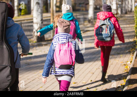 Les enfants vont à l'école sur le trottoir avec un amusement company Banque D'Images