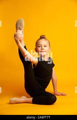 Petite danseuse danseur en étendant les jambes pendant l'entraînement Banque D'Images