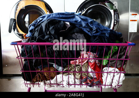 Photo d'un tas de linge propre dans un panier en face de machines à laver Banque D'Images