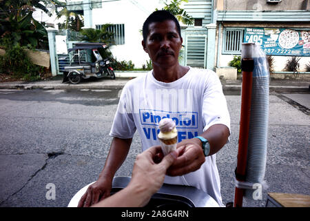 ANTIPOLO CITY, PHILIPPINES - le 2 novembre 2019 : La crème glacée les mains du vendeur une glace dans un cône à un client. Banque D'Images