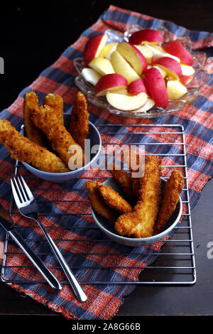 Photo de plats préparés poulet croustillant et bandes de poissons et bol de tranches de pomme et poire Banque D'Images