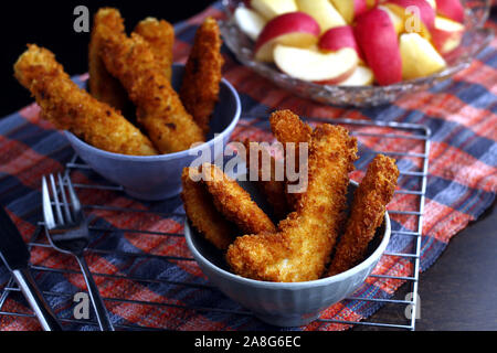 Photo de plats préparés poulet croustillant et bandes de poissons et bol de tranches de pomme et poire Banque D'Images