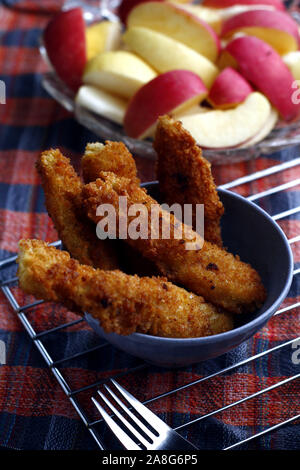 Photo de plats préparés poulet croustillant et bandes de poissons et bol de tranches de pomme et poire Banque D'Images