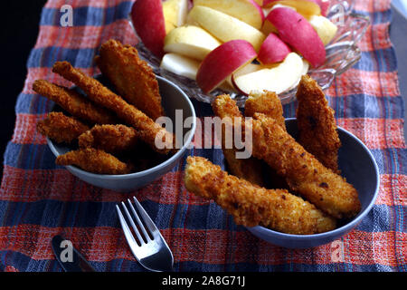 Photo de plats préparés poulet croustillant et bandes de poissons et bol de tranches de pomme et poire Banque D'Images
