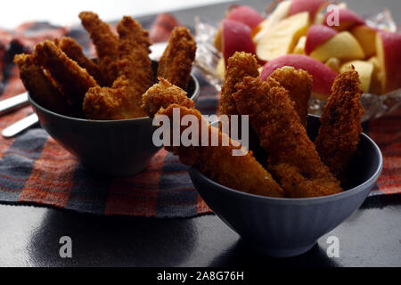 Photo de plats préparés poulet croustillant et bandes de poissons et bol de tranches de pomme et poire Banque D'Images