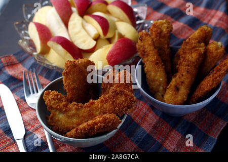 Photo de plats préparés poulet croustillant et bandes de poissons et bol de tranches de pomme et poire Banque D'Images