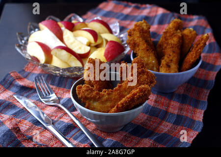 Photo de plats préparés poulet croustillant et bandes de poissons et bol de tranches de pomme et poire Banque D'Images