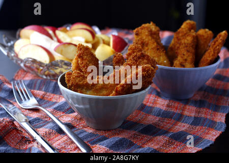 Photo de plats préparés poulet croustillant et bandes de poissons et bol de tranches de pomme et poire Banque D'Images