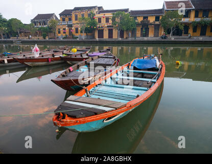 Close up d'un bateau de pêche en bois coloré avec des yeux peints amarré sur la rivière Thu Bon à Hoi An Vietnam avec de l'or dans les bâtiments en stuc riverfront Banque D'Images