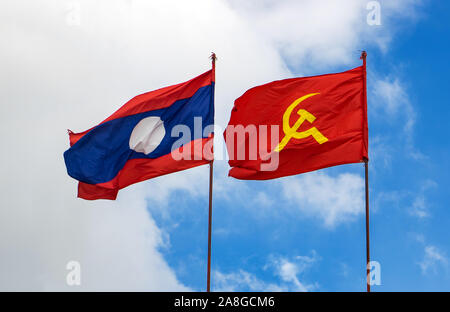 La République drapeau national avec le drapeau rouge avec des symboles communistes une faucille et un marteau voler dans un ciel bleu, Laos Banque D'Images