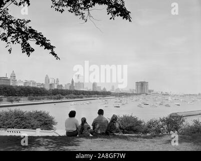 Une famille est assis par le Shedd Aquarium le long de solidarité donnant sur le port de Chicago Monroe et le secteur nord d'horizon, ca. 1960. Banque D'Images