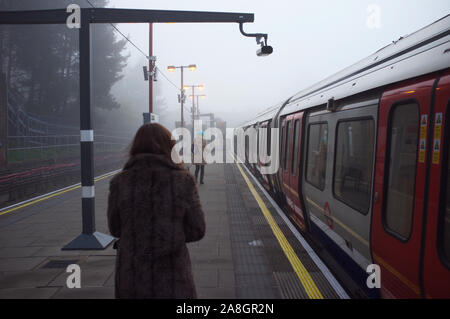 Nord-ouest de Londres, la herse sur la colline, les navetteurs marche sur la plate-forme de la station de métro, prendre le tube de travailler dans le brouillard matin de tiques. Banque D'Images