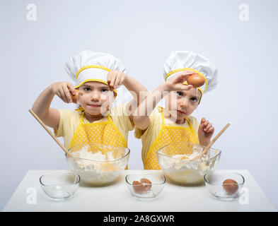 Les jeunes sœurs, la cuisson d'un gâteau ensemble en studio Banque D'Images