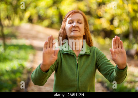 Senior woman est l'exercice pratique du Tai Chi dans le parc. Banque D'Images