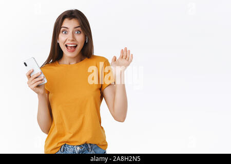 Gai, heureux jeune femme des écouteurs sans fil comme cadeau d'anniversaire, cant hide bonheur, serrer la main heureuse et heureux, holding smartphone Banque D'Images