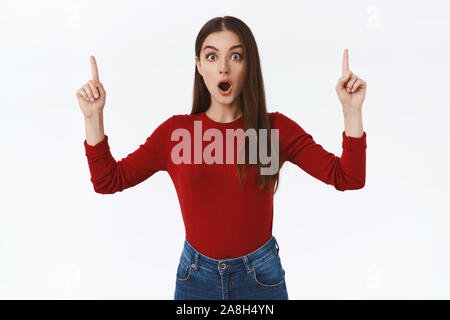 Choqué étonné féminin brunette Girl in red sweater, bouche ouverte est demandé et fasciné, émerveillé, regarder la caméra regard impressionné, comme pointer l'appareil photo Banque D'Images