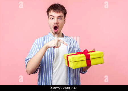 Portrait of young brown brun avec petit barbe et moustache en chemise décontractée à pointage boîte-cadeau avec étonnement le visage, surpris par unexpecte Banque D'Images