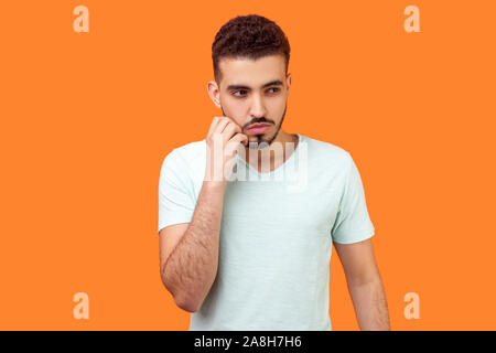 Pense que le plan d'action. Portrait de l'homme réfléchi perplexe avec barbe brune en blanc T-shirt rayer sa joue et de penser plus difficile question indo. Banque D'Images