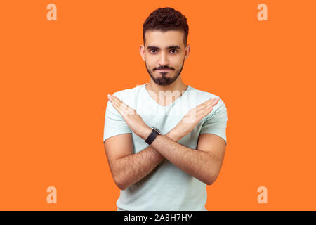 Non, absolument pas. Portrait d'homme avec barbe brune déterminée en t-shirt blanc montrant x Ouvrir une session avec les mains croisées, stop, c'est l'e Banque D'Images