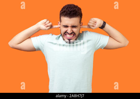 Vous ne voulez pas écouter plus. Portrait de brunette homme debout avec grimace irritée, étroitement couvrant ses oreilles pour ne pas entendre des sons forts ennuyeux. ind Banque D'Images