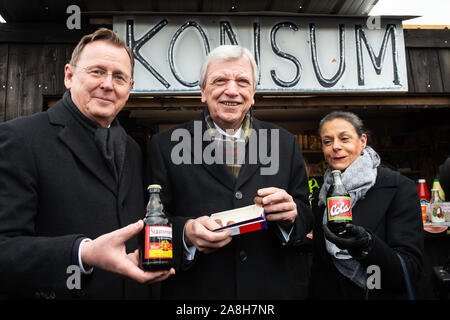 09 novembre 2019, la Thuringe, Großburschla : Volker Bouffier, CDU (M), Ministre-président de Hesse, Bodo Ramelow (Die Linke), Ministre-président de Thuringe, et sa femme Germana Alberti de la cour se placer en face d'un marché de consommation spécialement mis en place pour la célébration. Les gouvernements d'état de Thuringe et de Hesse célébrons 30 ans de la chute du Mur de Berlin - nous vivons la liberté'. Photo : Swen Pförtner/dpa Banque D'Images