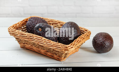 Les avocats brun foncé ( Bilse cultivar ) dans le panier carré sur les tableaux blancs 24. Banque D'Images