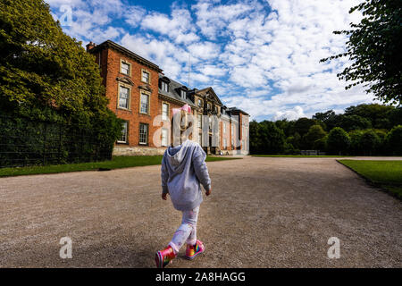 Une petite fille explore les motifs de Dunham Massey, regardant le daim et la maison et les jardins, la campagne en UK Banque D'Images