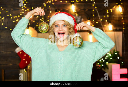 Dernières préparations. vacances d'hiver décorations. bonne année.. préparation de noël Girl in red santa claus hat. Décoration Nouvel an boule. Cheerful woman. décorer l'arbre de Noël. Banque D'Images