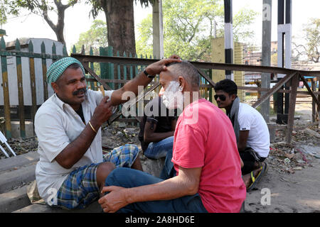 Salon de coiffure de la rue un homme de rasage à l'aide d'une lame de rasoir dans une rue de Kolkata, West Bengal, India Banque D'Images