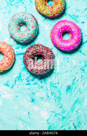 Gros plan du beau multicolore doux beignets dans une assiette sur grunge fond bleu avec l'exemplaire de l'espace. Alimentation, restaurant, boulangerie concept Banque D'Images