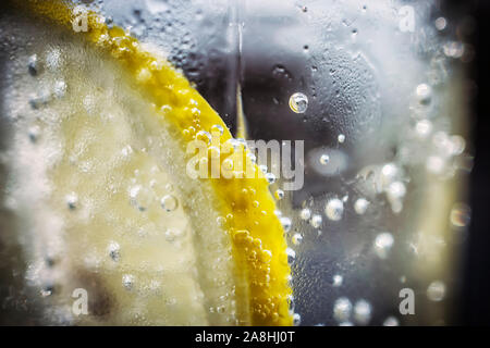 Un plan macro sur un morceau de citron dans un verre d'eau gazeuse Banque D'Images