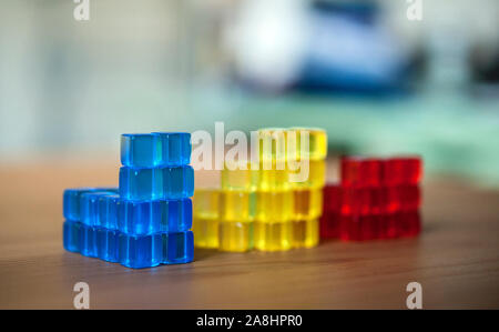 Les cubes colorés empilés. Comparaison, illustration, jeux de construction, jaune, bleu, rouge. Banque D'Images