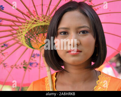 Fille birmane est titulaire d'un parasol en papier colorés traditionnels et de pose pour la caméra lors d'une célébration bouddhiste traditionnelle. Banque D'Images