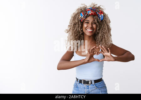 Amical et attentionné joyeux bon-à la femme afro-américaine avec afro blonde hairstyle, souriant à pleines dents, sentiments sincères heureux partager coeur show Banque D'Images