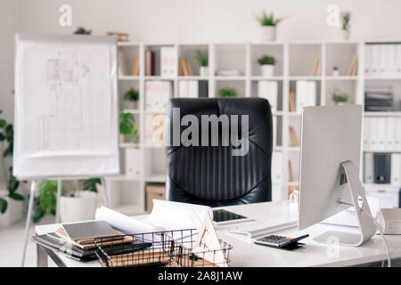 Lieu de travail avec bureau, fauteuil en cuir noir, tableau blanc, écran d'ordinateur Banque D'Images