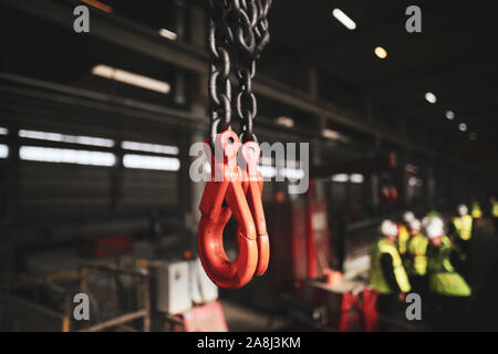 Profondeur de champ (selective focus) image avec crochets de levage grue industrielle rouge à l'intérieur d'une usine. Banque D'Images