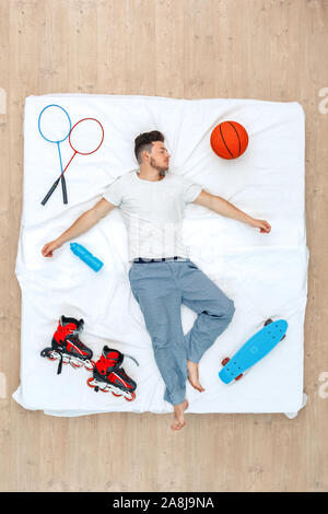 L'heure du coucher. Guy lying on bed top view Banque D'Images