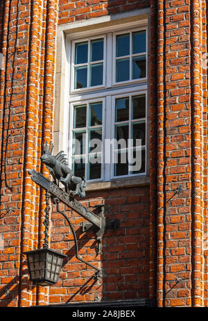 Commerce de fer de fonte et de la lanterne signe illustrant sous le winfow lézard sur bricky mur de bâtiment ancien à Gdansk, Pologne Banque D'Images