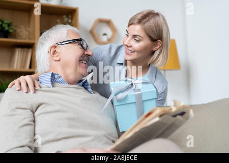 Jeune femme blonde mature son père avec coffret bleu présent Banque D'Images