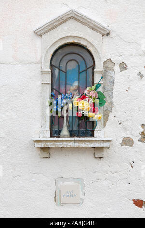 Culte avec des fleurs et une statue de la Vierge Marie dans le mur d'un bâtiment à Venise, Italie Banque D'Images