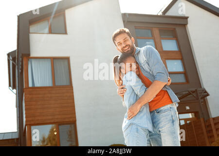 Mixed Race Mariage. Young man and woman standing outdoors près de nouvelle chambre hugging cheerful in sunlight Banque D'Images