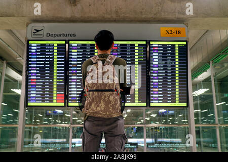 Jeune homme avec sac à dos à la recherche floue à l'écran d'affichage d'information de vol à l'aéroport. Banque D'Images