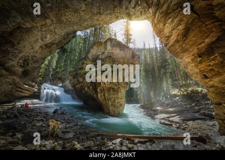 Grotte naturelle par Johnston Creek, un affluent de la rivière Bow, à Johnston Canyon, parc national de Banff dans les Rocheuses canadiennes. Journée ensoleillée, eaux turquoise Banque D'Images