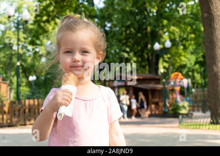 Sourire petite fille mange une glace dans le parc Banque D'Images